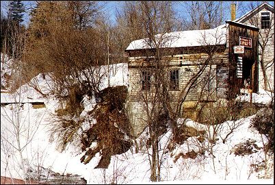 old mill building over frozen waterfall in spring