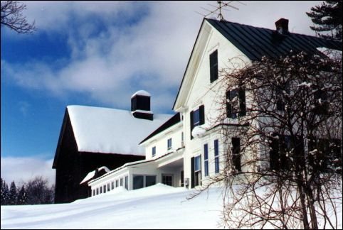 large white house and barn surrounded by snow